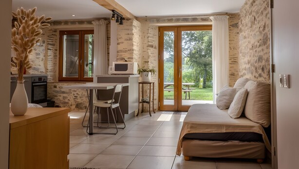 A bedroom with a bed, a desk, and a view of the outdoors.