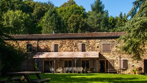 A stone building with a thatched roof, outdoor seating, and a picnic table.