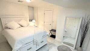 Quarto com cama, mesa de cabeceira, espelho, porta e piso de mármore.