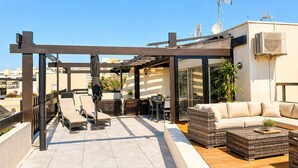 Una terraza en la azotea con pérgola, mobiliario exterior, un sofá y un comedor.