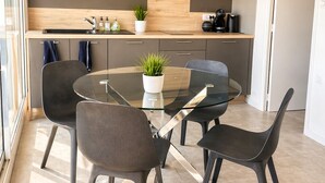 Una cocina moderna con una mesa de comedor de cristal, sillas oscuras y un microondas.