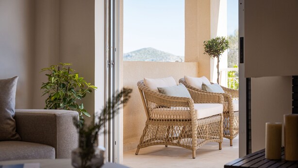 A room with a sofa, wicker furniture, a potted plant, and a view of the outdoors. - Aegean Essence Villa (Saronikos)