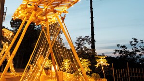 A wooden structure with lights, surrounded by trees and a fence. - SWAR Kasauli - Suites Cuisine Cave Club (Kasauli)