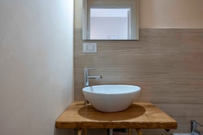 A bathroom with a white vessel sink, wooden countertop, and a mirror above the sink. - Suite Ionio - Teresita Guest House (Gallipoli)