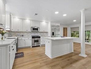 A modern kitchen with white cabinetry, stainless steel appliances, and a large island.