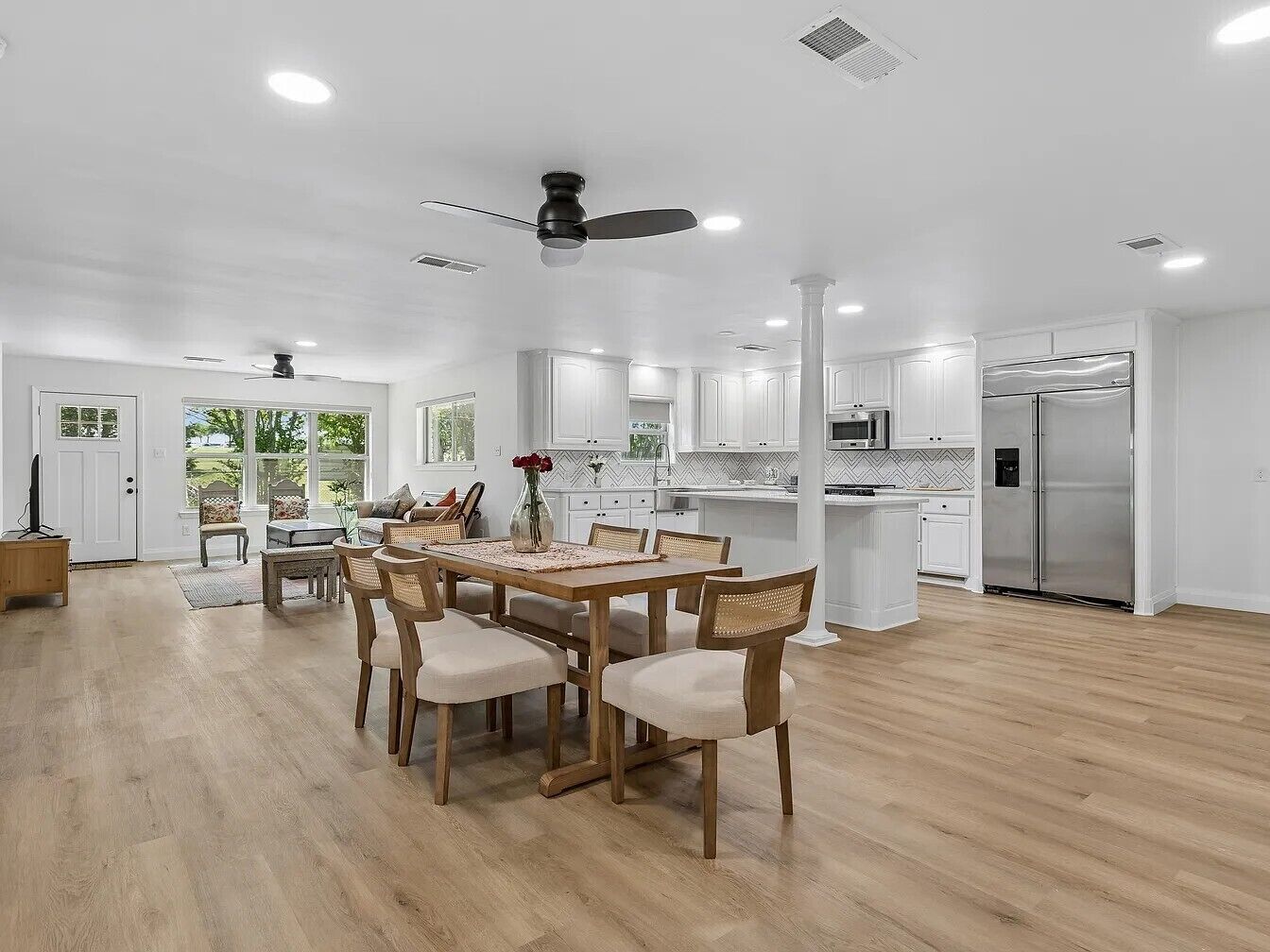 A spacious kitchen with a dining area, wooden flooring, and a ceiling fan.