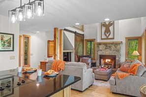 Amplia sala de estar con chimenea, una mesa de comedor con platos, y un sofá grande.