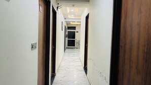 Un couloir avec des portes en bois, un sol en marbre et un plafond doté d’un éclairage encastré.