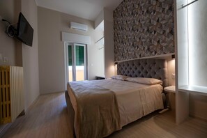 Ein Schlafzimmer mit einem Bett, einem an der Wand montierten Fernseher, einer Heizung und einem Fenster mit Blick.