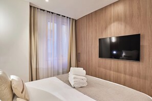 A hotel room with a bed, a TV mounted on the wall, and a window with curtains. - New Apartment Notre Dame de Paris/luxembourg (Paris)