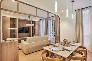 Ein modernes Wohnzimmer mit einer Couch, einem Esstisch für sechs Personen und einem Fernseher.