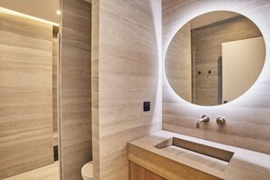 Ein modernes Badezimmer mit einem großen Spiegel, einem Waschbecken und einer Toilette.
