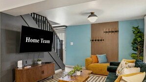 Una sala de estar moderna con una escalera, un televisor de pantalla plana, un sofá y una mesa de centro.