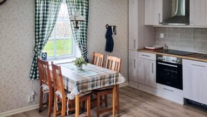 A kitchen with a dining table, chairs, a stove, and a window with curtains. - 4 Star Holiday Home in Bralanda (Bralanda)