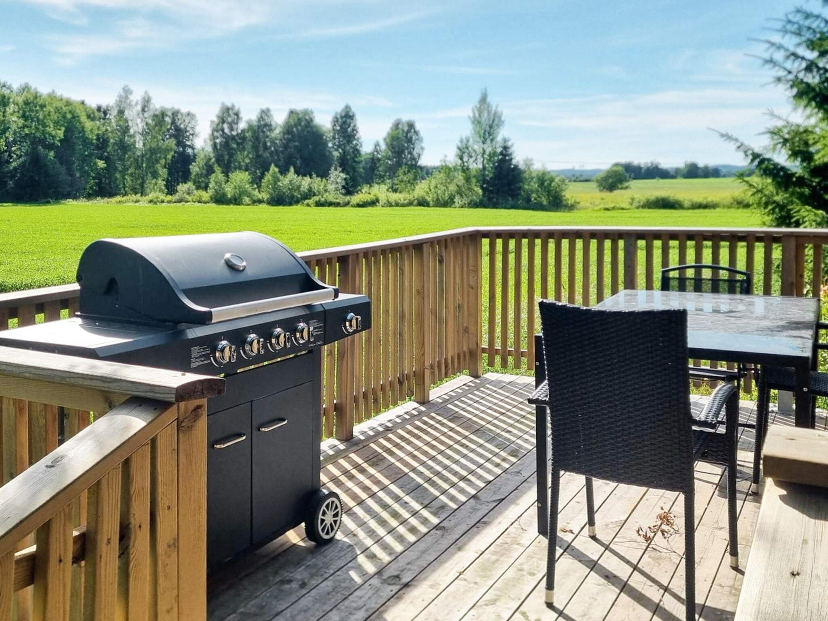 A deck with a grill, a table, and chairs.