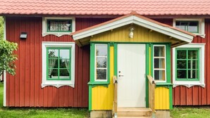 A red wooden house with a white door, green window frames, and a yellow porch. - 4 Star Holiday Home in Bralanda (Bralanda)
