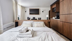 A hotel room with a large bed, wooden wardrobe, flat-screen TV, and a small table with a kettle. - Beautiful Studio With AC - Louvre Palais Royal (Paris)