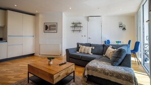 Een moderne woonkamer met een bank, salontafel en een eethoek met stoelen.