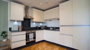 Een moderne keuken met witte kasten, een roestvrijstalen afzuigkap, een magnetron en een inbouwoven.