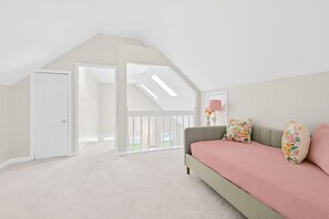 Un dormitorio con techo inclinado, una cama con almohadas florales, una mesita de noche y un ventanal con vistas.