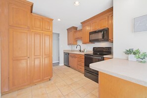 A kitchen with wooden cabinets, a microwave, an oven, and a dishwasher. - Newly Renovated VB Retreat | Comfort & Space Home (Virginia Beach)
