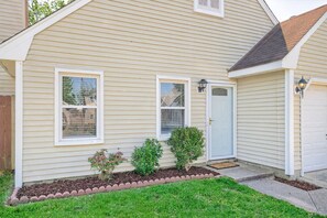 A single-story house with a front door, two windows, and a small porch area with plants. - Newly Renovated VB Retreat | Comfort & Space Home (Virginia Beach)