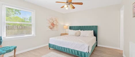 A bedroom with a bed, a ceiling fan, a window with blinds, a chair, and a rug.