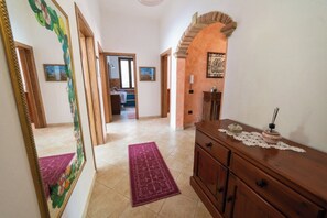 A hallway with a wooden cabinet, a mirror, and a rug. - Timeless house, 10 minutes from the sea - Quiet & Roomy (Riola Sardo)