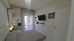 Une chambre à coucher avec un lit, des lampes de chevet, une télévision, un miroir et une porte.