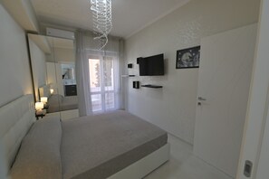 A bedroom with a bed, bedside lamps, a TV, a mirror, and a door. - Double Room 1 with Wi-Fi and Air Conditioning (Baia Verde)