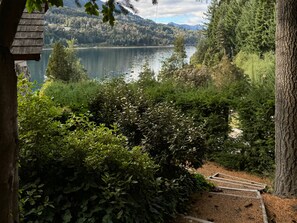 Vista de um lago rodeado por floresta densa e montanhas.