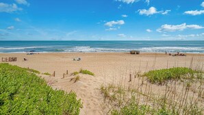 Ein Strand mit Sand, Wellen und blauem Himmel.