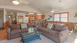 Ein Wohnzimmer mit zwei Sofas, einem Glastisch und einem Essbereich mit Holzsesseln und einem Tisch.
