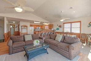 A living room with two couches, a glass coffee table, and a dining area with wooden chairs and a table. - JL #305 - Time Out I - Oceanfront Duplex - Pool (Kill Devil Hills)