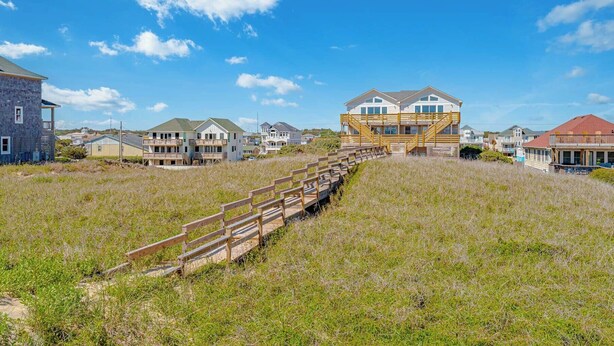 En ejendom ved stranden med en trætrap, der fører op til et hus med flere balkoner.