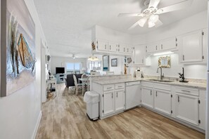 A modern kitchen with white cabinetry, a marble countertop, and a ceiling fan. - JL S-2B - Oceans 11 - The Sands Condos - Oceanfront - Community Pool (Kill Devil Hills)