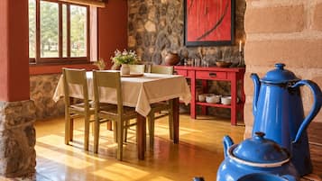 Un comedor con pared de piedra, una mesa con sillas y teteras azules.