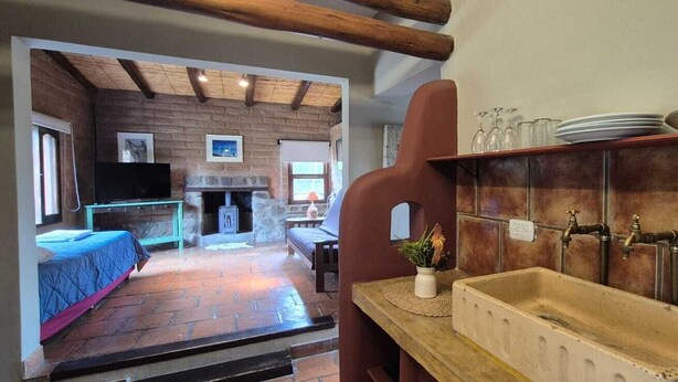 Un interior rústico con chimenea de piedra, televisor y comedor.