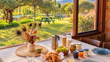 Une table dressée pour le petit-déjeuner, avec vue sur un jardin et des montagnes.