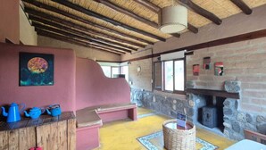 Un interior rústico con chimenea de piedra, vigas de madera y un banco.