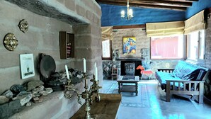 Un interior rústico con chimenea de piedra, un banco de madera y una araña.