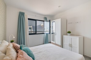 Un dormitorio con cama, cortinas, ventana, armario y planta.