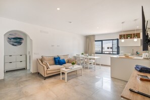 A modern living room with a sofa, coffee table, and dining area.