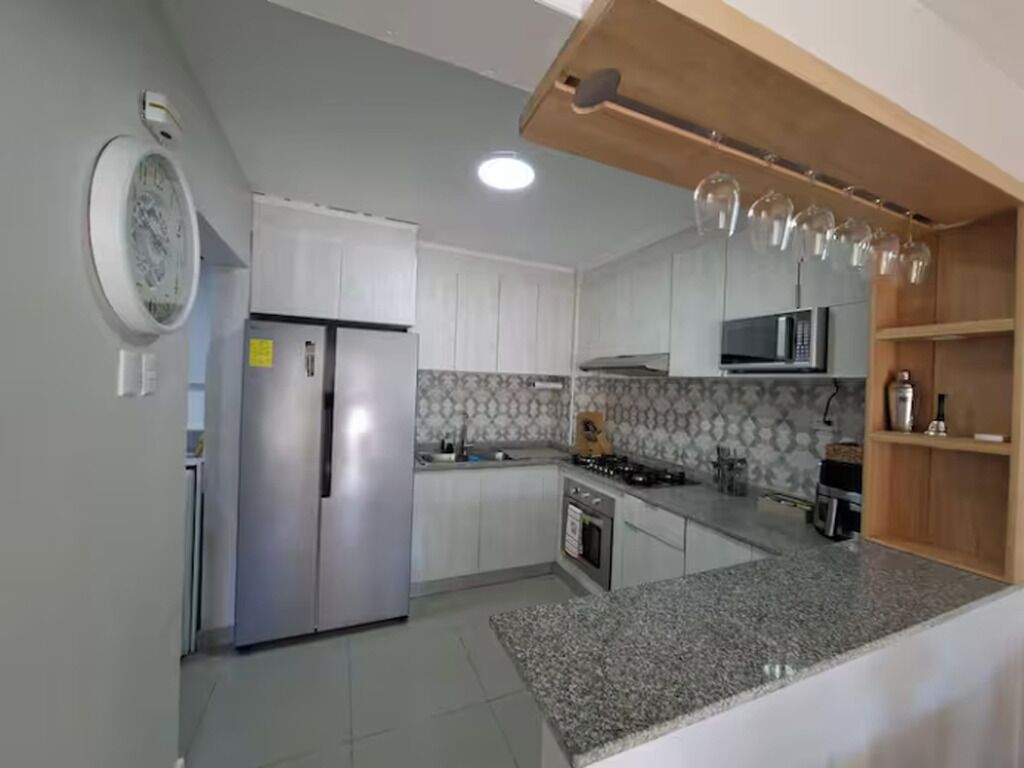 Une cuisine avec des meubles blancs, un plan de travail en granit, un four à micro-ondes et une cuisinière.