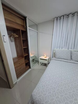 A bedroom with a bed, a bedside table with a lamp, a wardrobe, and a sliding door closet. - Nice Apartment in Santo Domingo with A/C, Wi-Fi, and Parking (Santo Domingo)
