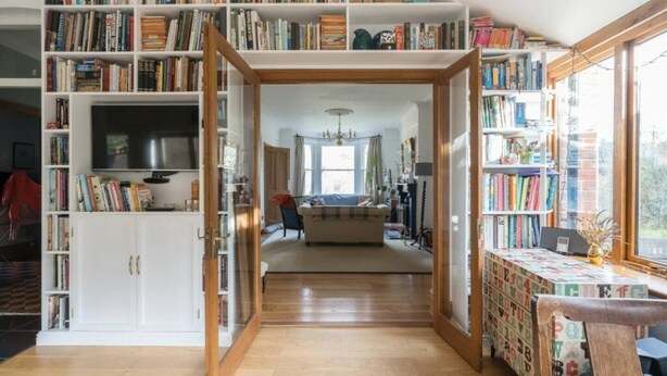 Ein geräumiges Zimmer mit einer großen Bücherwand, einem Fernseher und einer gemütlichen Sitzecke.