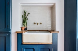 A kitchen with a white sink, blue cabinets, and a potted plant. - Cotswolds home gorgeous location (Nailsworth)