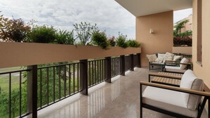 Ein Balkon mit einer Couch, einem Tisch, einer Brüstung und Blick ins Grüne.