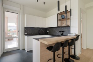 A modern kitchen with a marble backsplash, wooden countertop, and black bar stools. - Modern and spacious 200m2 apartment, ideal for 6 people, located on the fifth floor of a building with lift.The accommodation is located in the San Siro area, a stone's throw from the famous San Siro Stadium and the Snai Hippodrome.The location is strate (Milan)