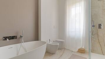 Ein modernes Badezimmer mit freistehender Badewanne, einem Bidet und einer Duschkabine.